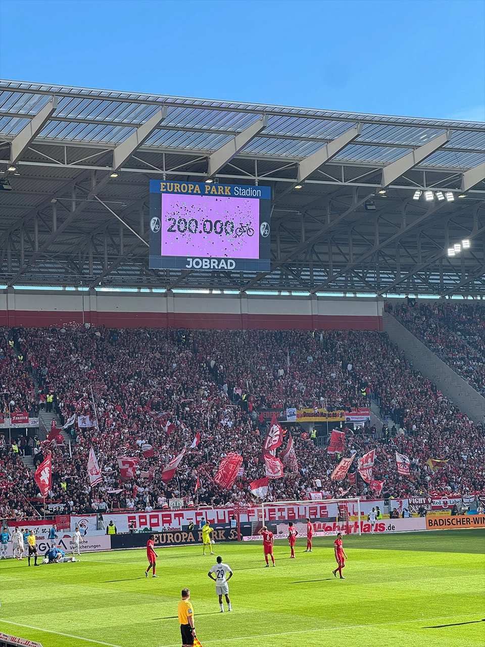 Der Screen im Europa-Park Stadion zeigt an, dass die 200.000 Fahrrad-Fan-Zahl erreicht wurde. Davor sieht man Spieler auf dem Spielfeld.